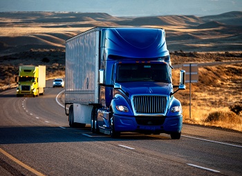 blue semi-truck driving down a freeway